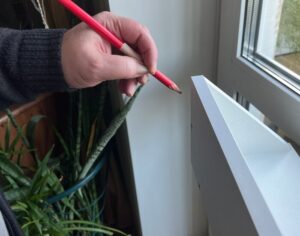 a hand holding a red pencil when learning how to redo countertops