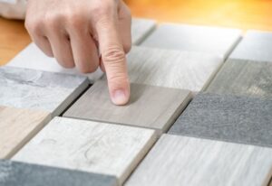 A closeup of a person pointing at stone material samples for countertops