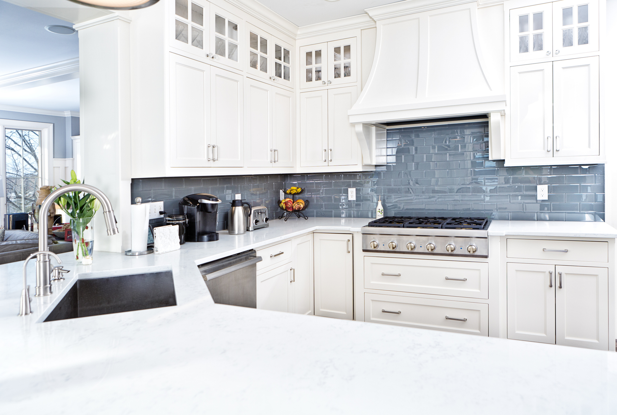 Modern kitchen featuring a light-colored marble or quartz countertop paired with a glossy blue-grey subway tile backsplash, showcasing a harmonious blend of textures and colors for a contemporary design.
