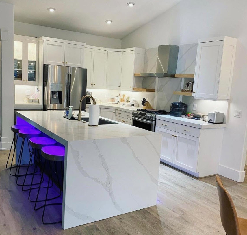 Modern kitchen with white cabinets and quartz waterfall island with bar stools