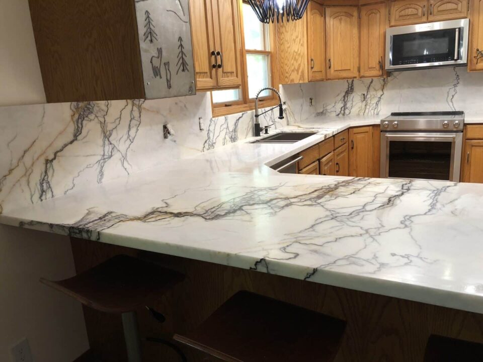 White kitchen with granite countertops, island, and modern tile backsplash
